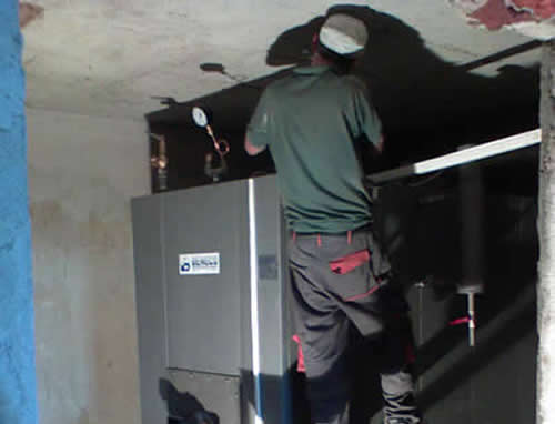 Работник завършва инсталацията на котел монтиран в помещение
