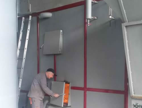 Работник отваря вратата на горивната камера на котел инсталиран в помещение
